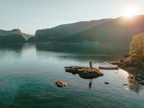 En naturvy från Norge med berg och vatten i solnedgång.