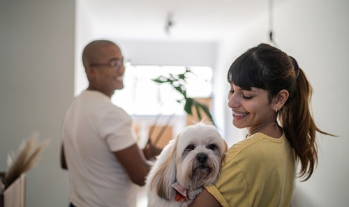 En kvinde som bærer sin hund, samtidig med at hendes mand bærer på Alfa flyttekasser og er på vej ind i sin nye lejlighed.