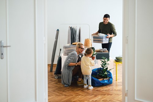 En familie på tre personer som forbereder sig på besigtigelse af deres bohave, set fra døråbningen.