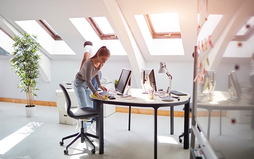 Professional cleaning personnel cleaning a bright top floor apartment with several windows to ensure top condition.